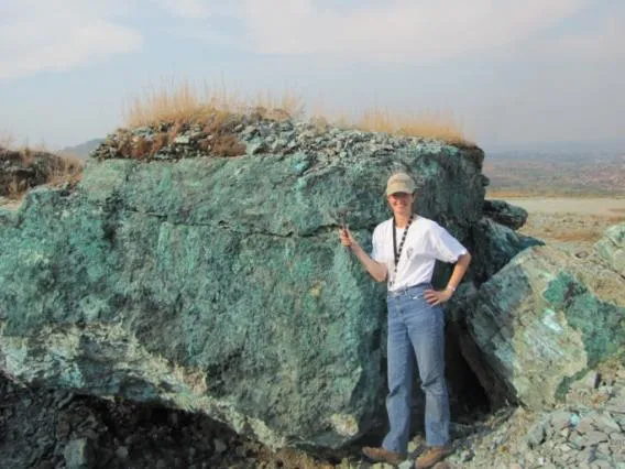 someone standing next to a big rock